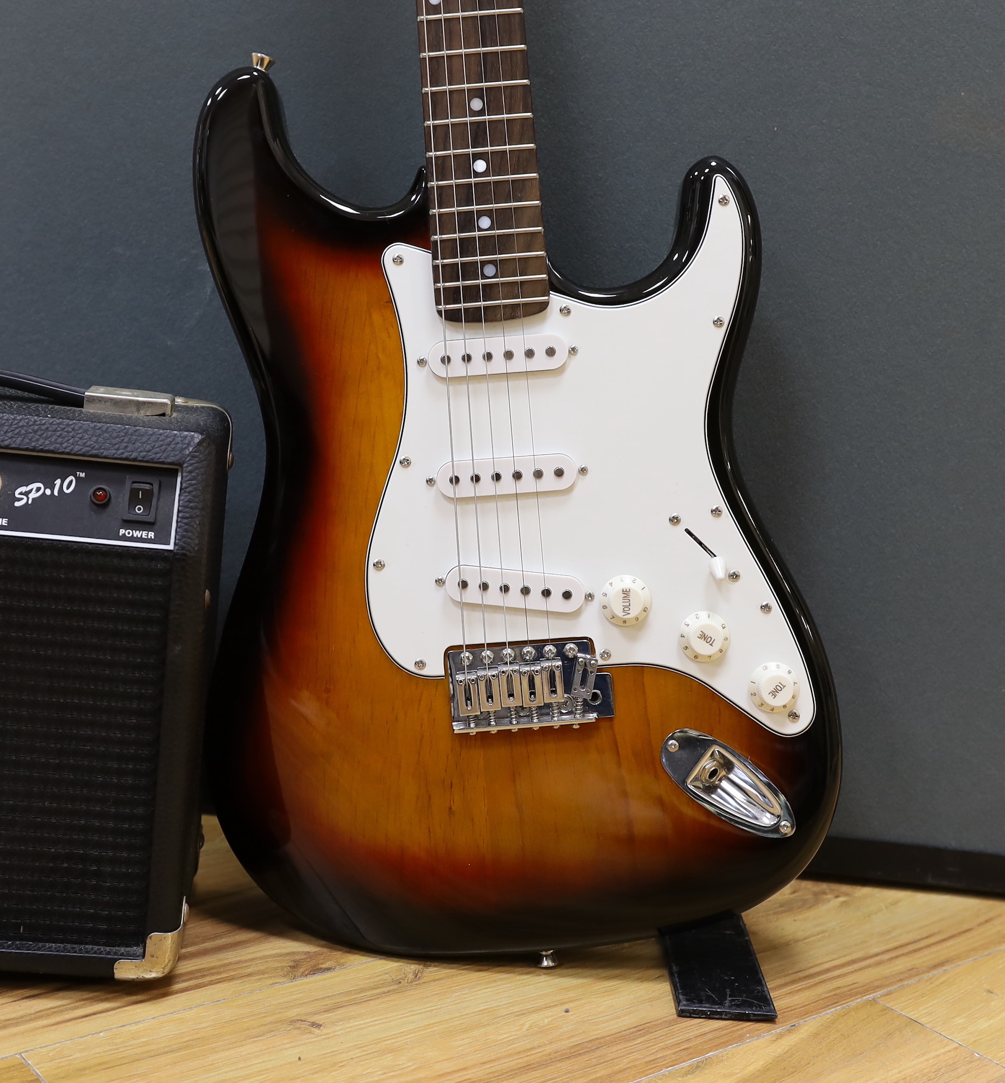 A Squier Strat by Fender Sunburst electric guitar made in China with rosewood neck, together with a small Squire SP-10 amp